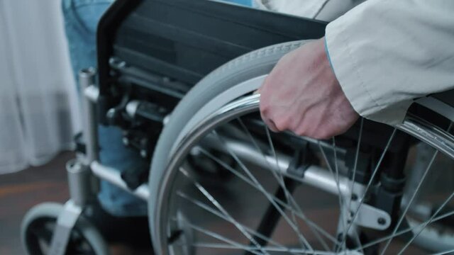 Man puts a hand on a wheel of a wheelchair