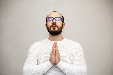 Obraz premium Portrait of a man with eyeglasses is praying. White background.