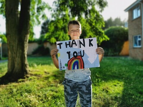 Young Boy with rainbow drawing and Thank You message for medical staff working through the Covid-19 Pandemic