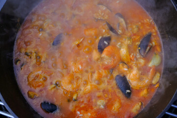 frying pan with rice, seafood and vegetable close-up. Paella cooking. Mediterranian cuisine. Spanish traditional meal.