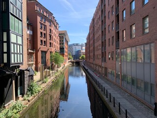 Naklejka premium canal with old buildings on both sides and reflections in the water. Taken in Manchester City centre. 