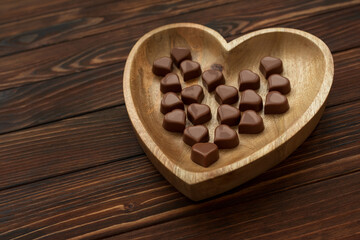Fototapeta na wymiar Chocolates hearts on brown wooden background. Top view. Copy space. Valentines day celebration concept