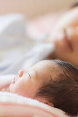 眠る新生児と見守る母親