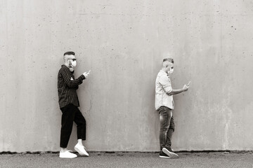 Cool men in a line using mobile phones while keeping social distance and wearing face medical mask - Friends watching video and texting with smartphone in a line during coronavirus outbreak - B & W