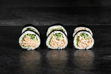 Sushi Rolls with salmon, avocado, omelet and Cream Cheese inside. Maki Futomaki Sushi Rolls with salmon on black background. Sushi menu. Japanese food.