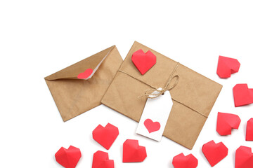 Envelope from craft paper with red heart and gift wrapped in brown craft paper, tied with twine with a bow, with label with heart, surrounded by several handmade red 3D paper hearts white background