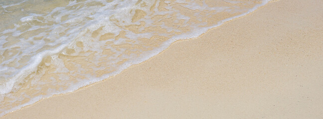soft wave of the sea on sandy beach texture in bright summer day for banner background