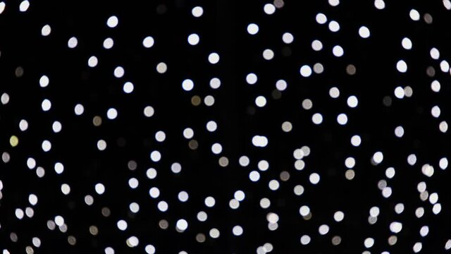 Abstract white blurred lights sparkling and glowing on black background. Christmas or New Year holiday concept