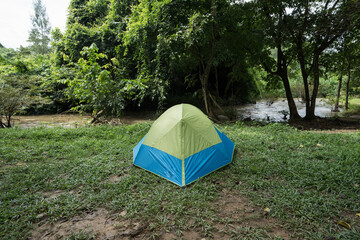 Camping tent on green grass field under cloudy sky