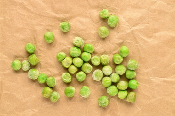 Fototapeta na wymiar Several frozen green peas, close-up, on brown paper.