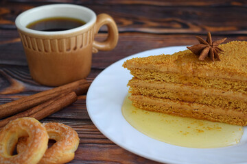 A piece of honey cake on a white plate on a wooden background.