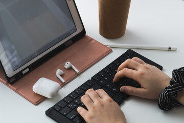 female person typing on a black bluetooth keyboard, working home office at a tablet computer
