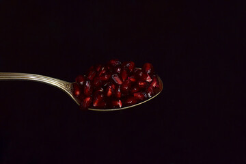Pomegranate seeds close-up in a spoon.