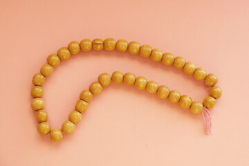 wooden rosary for prayer on a pink background