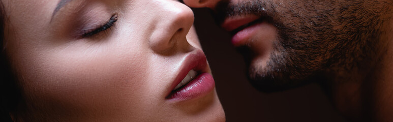 partial view of sensual woman face to face with man on dark background, banner