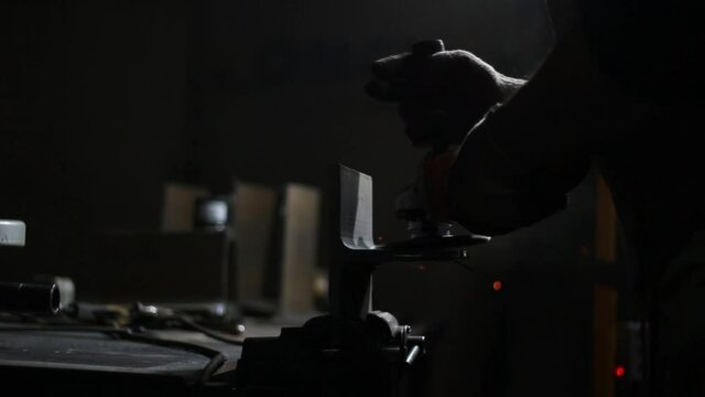 Metal processing with a grinder. The master grinds the steel. Sparks from the high friction of the grinder on the workpiece surface. Operation of a disk electric tool. 