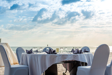 Table setting for an event party or wedding reception at the beach and beautiful sky.