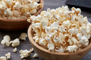 A closeup of two wooden bowls with fresh popcorn