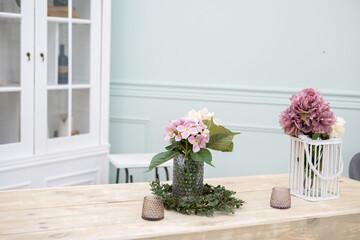 pink flowers stand in a glass vase on a light wooden table. Flowers in the interior