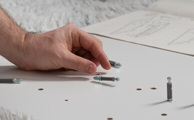 close-up of a hand and a falling dowel on a light board. Furniture assembly concept.