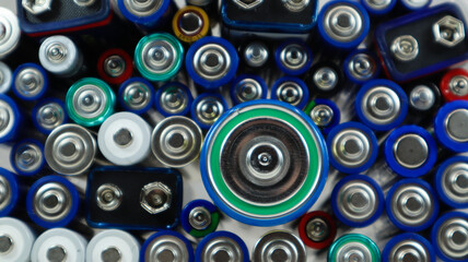 Lots of used household alkaline batteries type AA, AAA, PP3, D, C, collected for recycling. Recycling and ecology problems. Top view of a background of used batteries of different types and sizes.