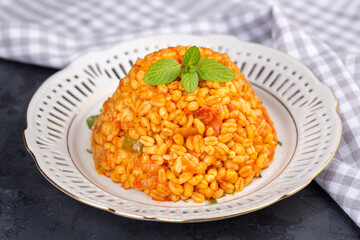 Traditional turkish bulgur pilaf with tomato sause in plate