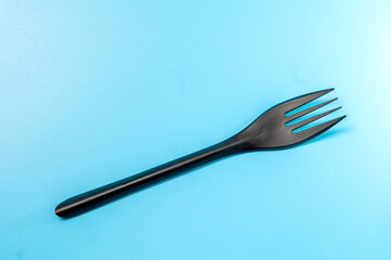 Black plastic fork on a blue background