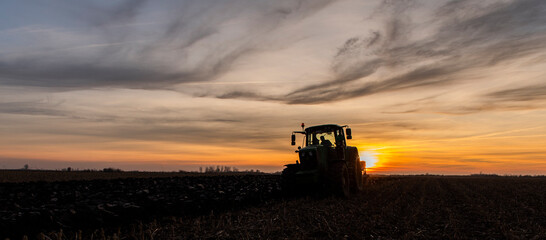 Fototapeta premium Tractor on the field during sunset.