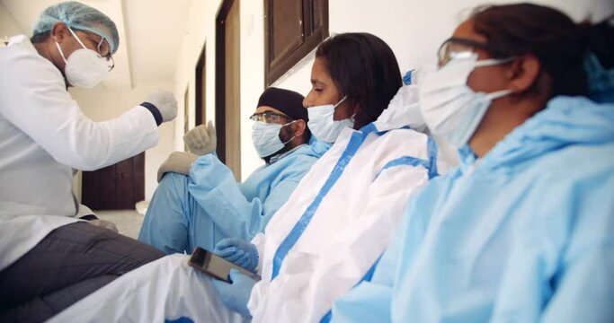 Slow-motion of doctor with lab coat with his colleagues take a break at teamwork as they bump their hands fist and high five after hours of selfless working at the frontline of the global pandemic 