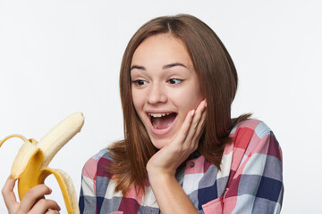 Portrait of a teen girl holding half peeled banana