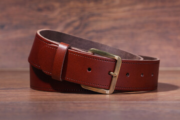 leather brown belt rolled up on a wood background