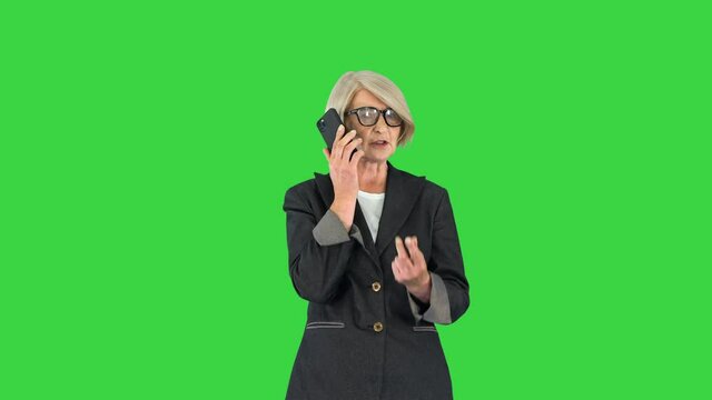 Stylish focused busy grey-haired lady ceo boss chief calling on a Green Screen, Chroma Key.