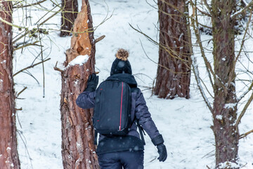 Woman leaning on the trunk of a tree broken by snow in the forest