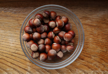 Hazelnut in glass bowl on wooden  background. Organic hazelnut harvest.
                      