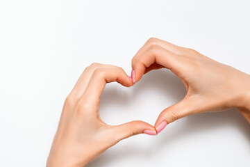 Young woman with hands shows a heart sign on a gray background. Concept for valentine's day, love,...