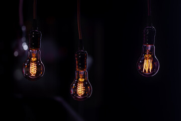 Three burning lamps on a blurred dark background.