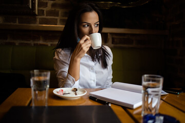 A young business woman is also working on a coffee break in a restaurant