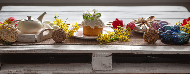 Easter composition with cake, tea, flowers, eggs and decoration details.