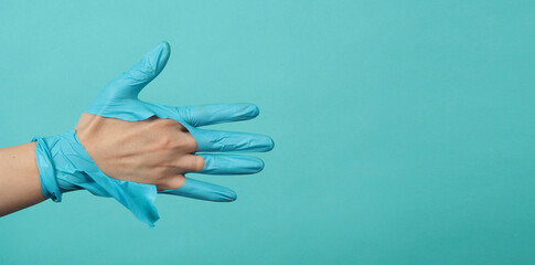 Close up of hand Wearing torn medical gloves or torn rubber gloves on blue and green or Tiffany Blue color background.monotone coclor.