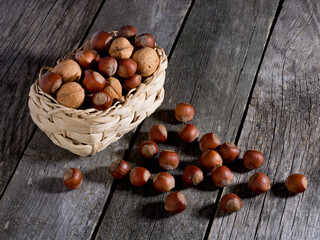 Hazelnuts and walnuts in a wicker basket on a wooden table.