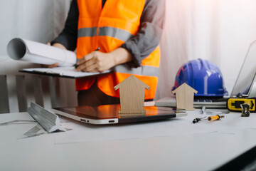 Two colleagues discussing data working and tablet, laptop with on on architectural project at construction site at desk in office