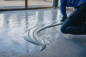 The worker applies gray epoxy resin to the new floor
