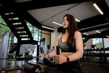 Fototapeta na wymiar Young beautiful woman in sportswear working out with machine in gym