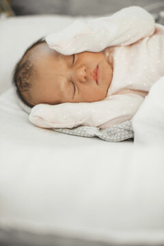 CLose up photo of a newborn baby sleeping in bed wearing warm clothes