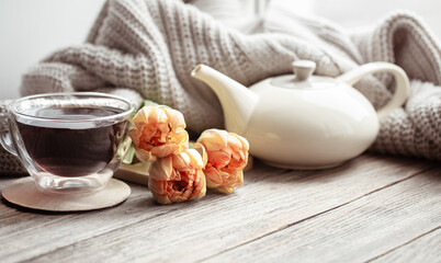 Cozy composition for Valentine's Day with a cup of tea, flowers and a knitted element.
