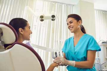 Female dentist in support of patient holds the patient hand setting her in a positive.