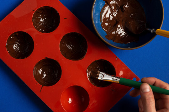 Painting a silicone mold with chocolate for hot chocolate bombs