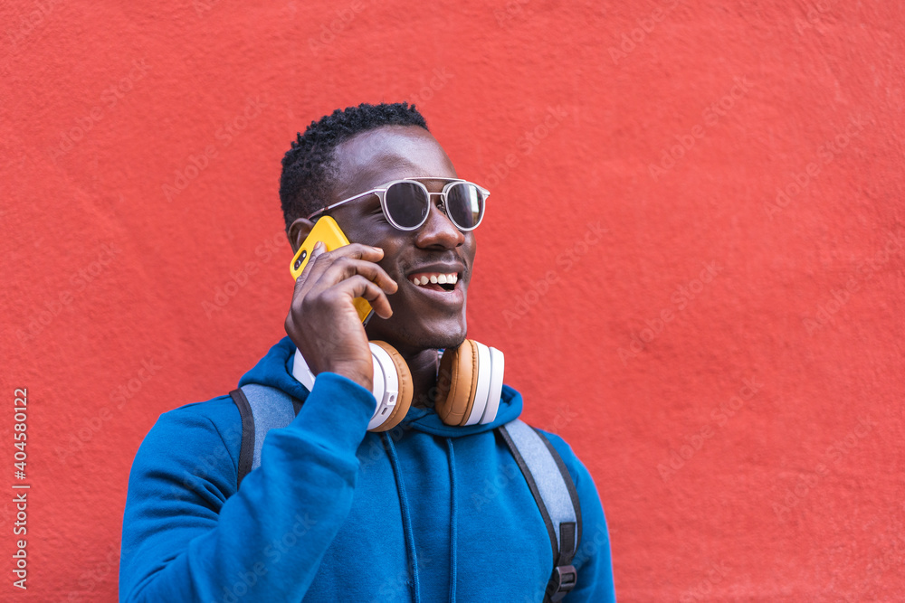 Wall mural Black Man Having Phone Call Wearing Blue Sweater Outdoors.