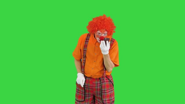 Clown with smartphone making a call on a Green Screen, Chroma Key.