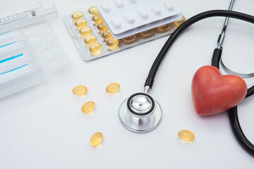 stethoscope and red artificial heart, vitamins and pills, on a white background
